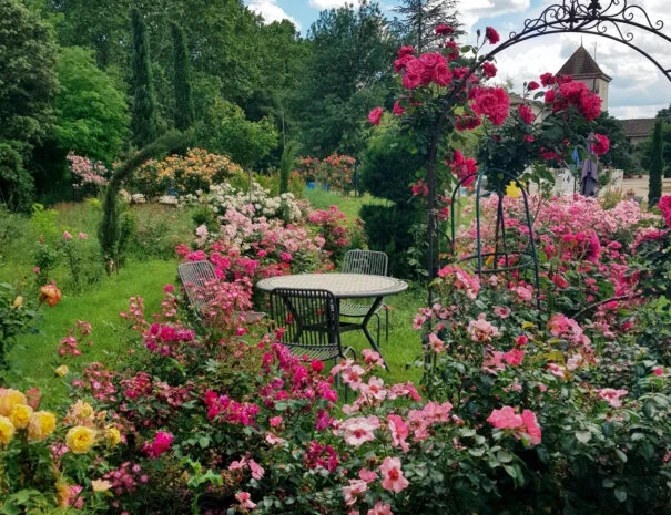 Salon de jardin romantique entouré de roses et arche fleurie au Mas de Pradines - Mariage Hérault