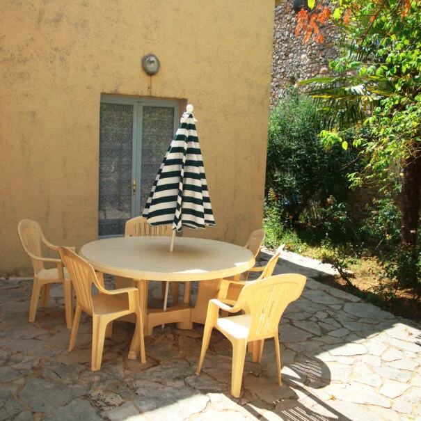 Terrasse ensoleillée d'un gîte du Mas de Pradines avec table et parasol, Hérault