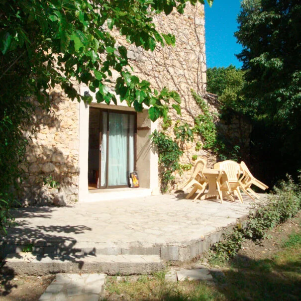 Terrasse en pierre avec mobilier bois d'un gîte du Mas de Pradines, Hérault