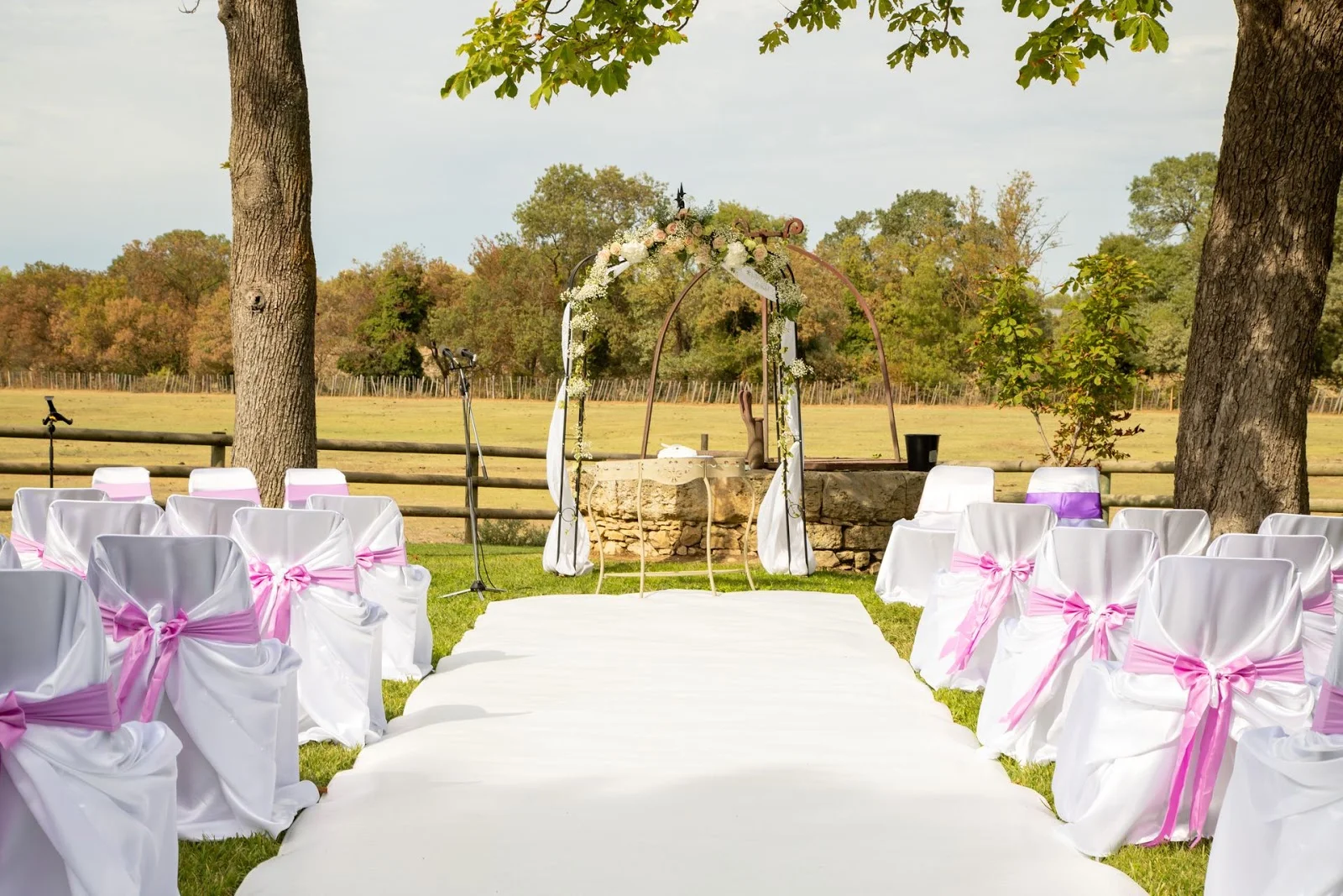 Mas du Pont Hérault - cérémonie laïque extérieure avec arche florale chaises blanches et nœuds roses