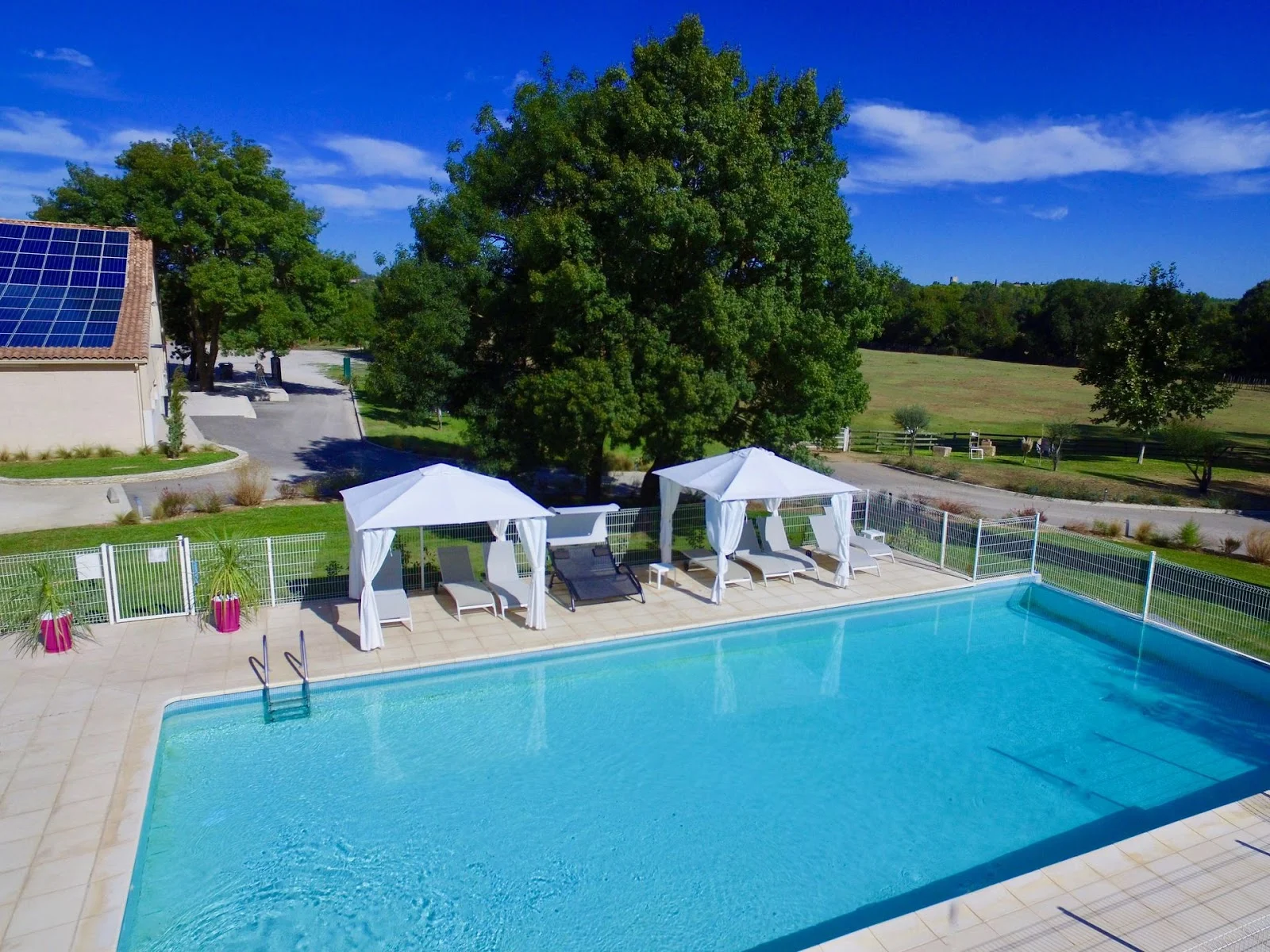 Mas du Pont Hérault - grande piscine rectangulaire avec transats et parasols blancs vue sur les champs
