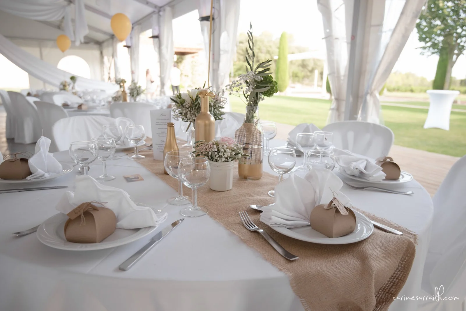 Table de mariage champêtre sous chapiteau au Mas Guilhem avec chemin de table jute et fleurs naturelles en Hérault