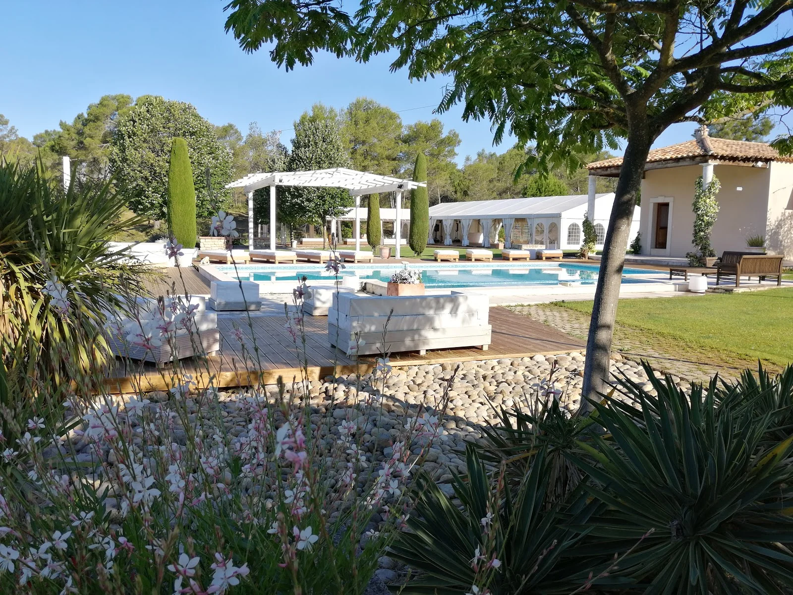 Jardin méditerranéen fleuri avec piscine et pergola blanche au Mas Guilhem domaine de mariage en Hérault