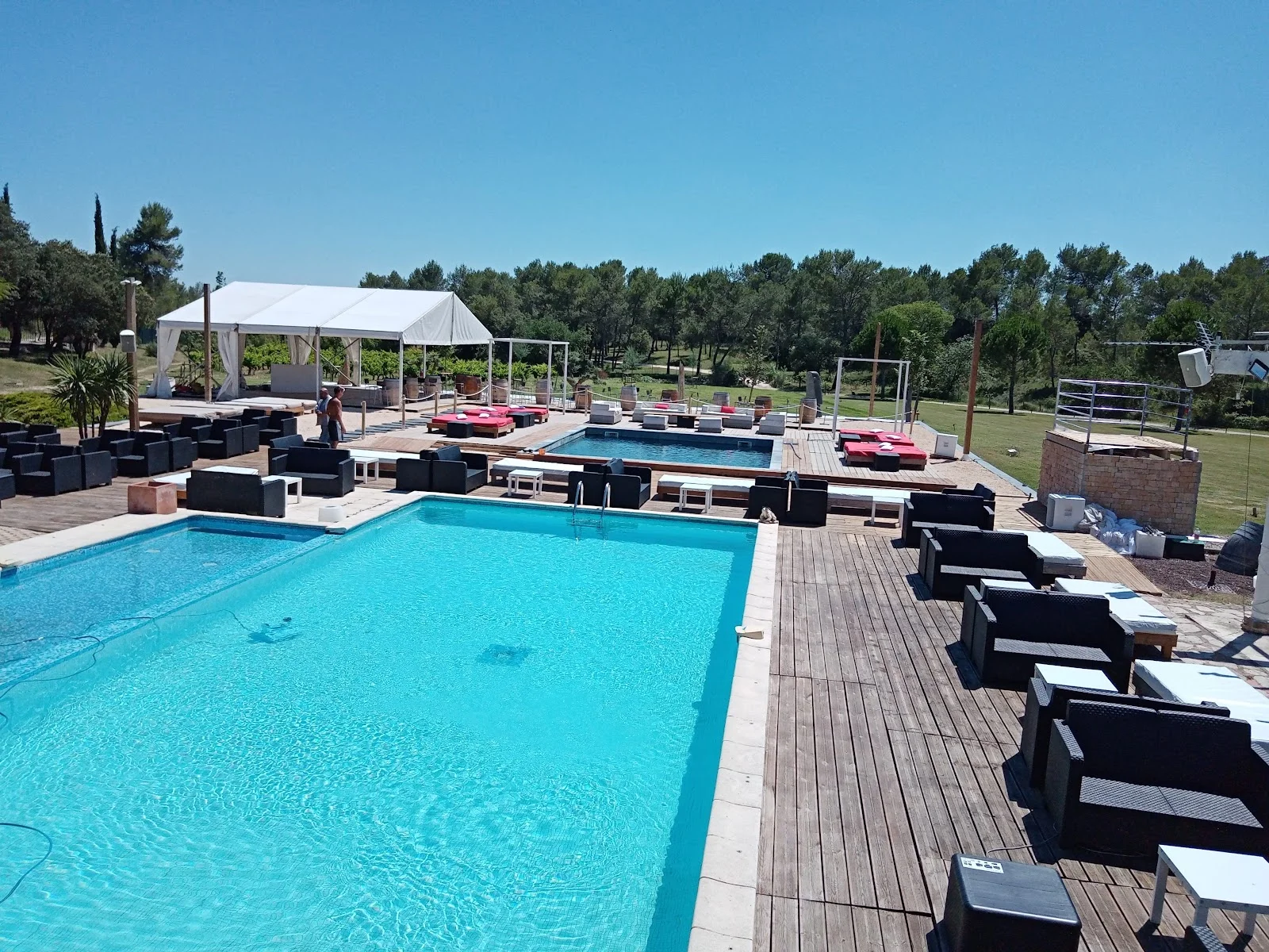 Grande piscine turquoise avec terrasse bois et transats au Mas Guilhem domaine événementiel en Hérault