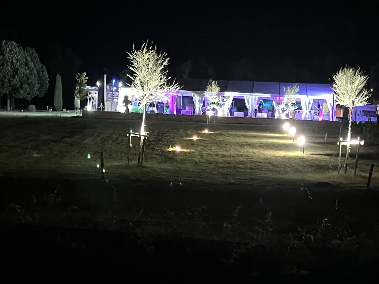 Soirée nocturne au Mas Guilhem avec chapiteau illuminé en violet et lanternes sur pelouse en Hérault