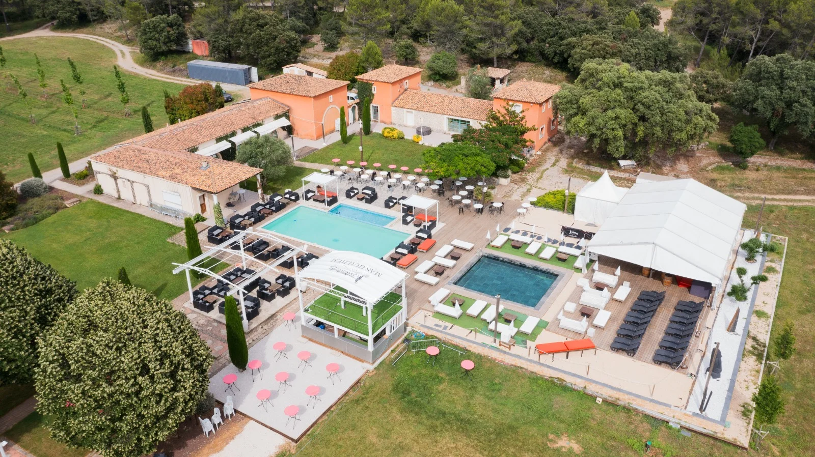 Vue aérienne du Mas Guilhem domaine de mariage avec piscines terrasses et chapiteau blanc en Hérault