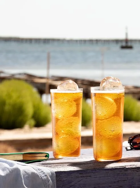 Cocktails Noilly Prat vermouth ambré servis sur une terrasse en bois face à la mer à Marseillan, Hérault