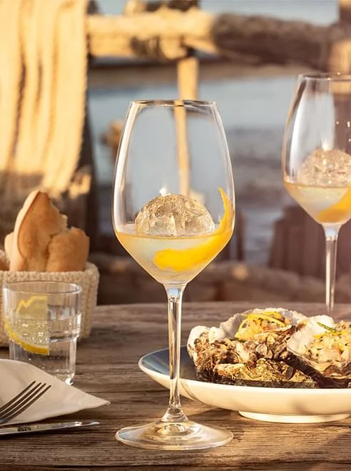 Verre de Noilly Prat blanc avec huîtres grillées au coucher du soleil à Marseillan pour un mariage en Hérault
