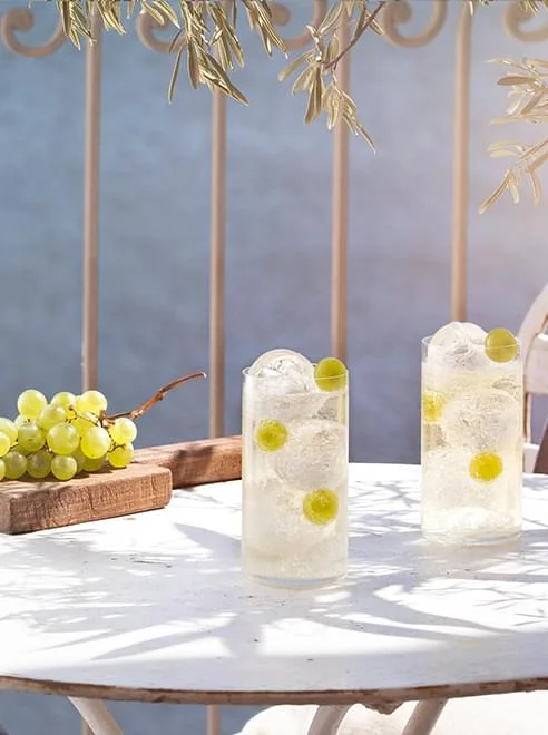 Cocktails Noilly Prat blanc avec raisins verts sur terrasse sous olivier à Marseillan, Hérault