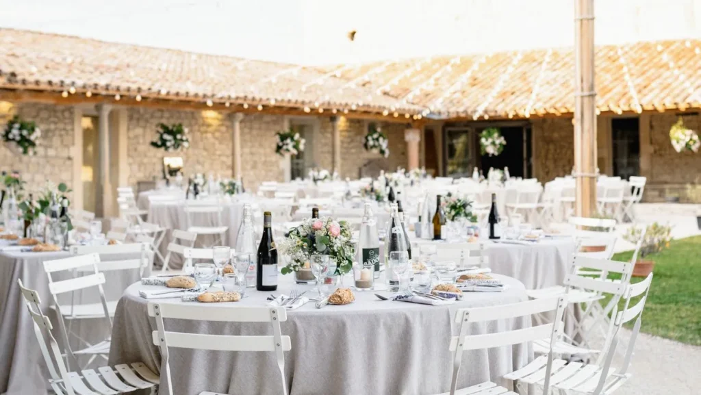 Vue d’ensemble de tables rondes dressées avec nappes grises et centres floraux en extérieur — Les Dînettes à Roulettes, traiteur de mariage à Aimargues