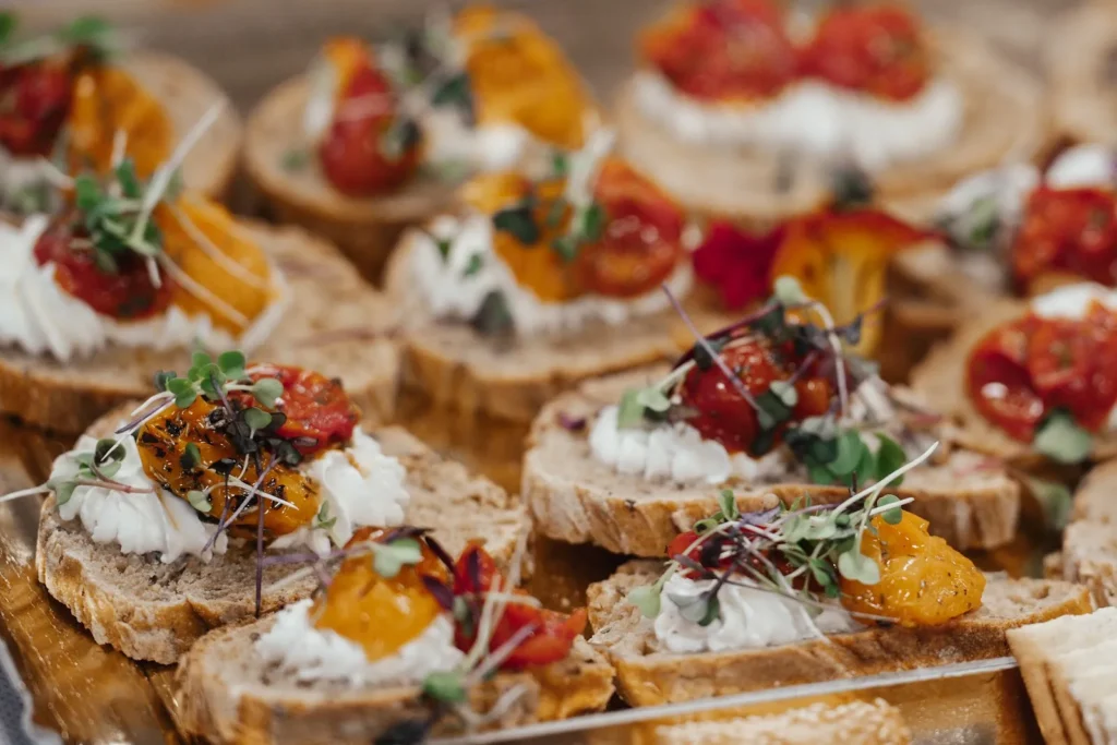 Un plateau de petites tranches de pain garnies de crème blanche, tomates cerises et micro-pousses — Hâpy Traiteur, mariages à Béziers