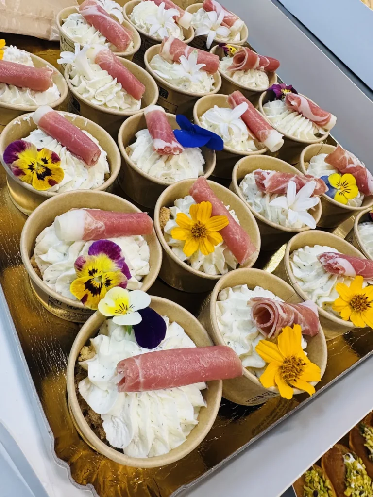 Verrines individuelles garnies de crème blanche, jambon cru et fleurs comestibles sur plateau doré — Hâpy Traiteur, Béziers