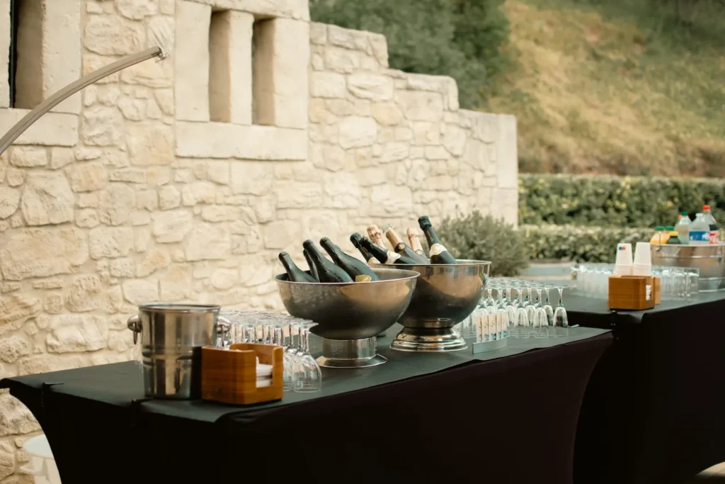 Table de bar extérieure avec seaux de champagne, vin et boissons non alcoolisées — L’Atelier Nomade, Ceyras