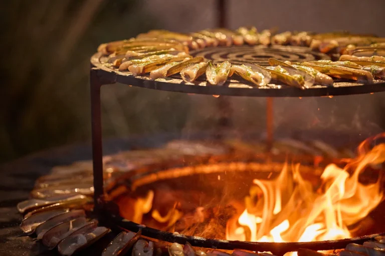 Couteaux de mer disposés sur une grille circulaire au-dessus d’un feu de bois ardent — L’Atelier Nomade, traiteur de mariage à Ceyras