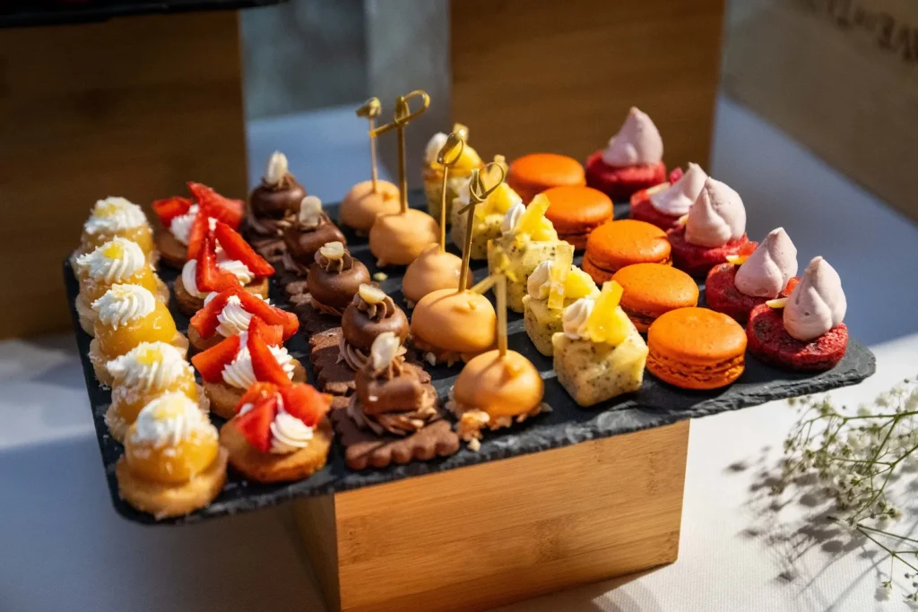 Plateau en ardoise de macarons orange, tartelettes aux fraises et gâteaux au citron — L’Atelier Nomade, Ceyras