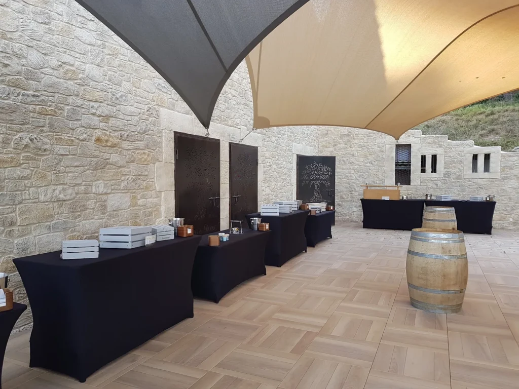 Tables de buffet drapées de noir, décorées de caisses en bois et bougies, avec tonneaux — L’Atelier Nomade, Ceyras