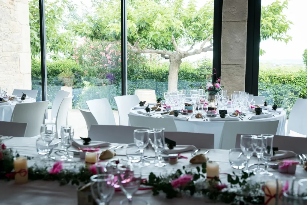 Tables de mariage dressées avec nappes blanches, vaisselle, bougies et décorations florales — L’Atelier Nomade, Ceyras