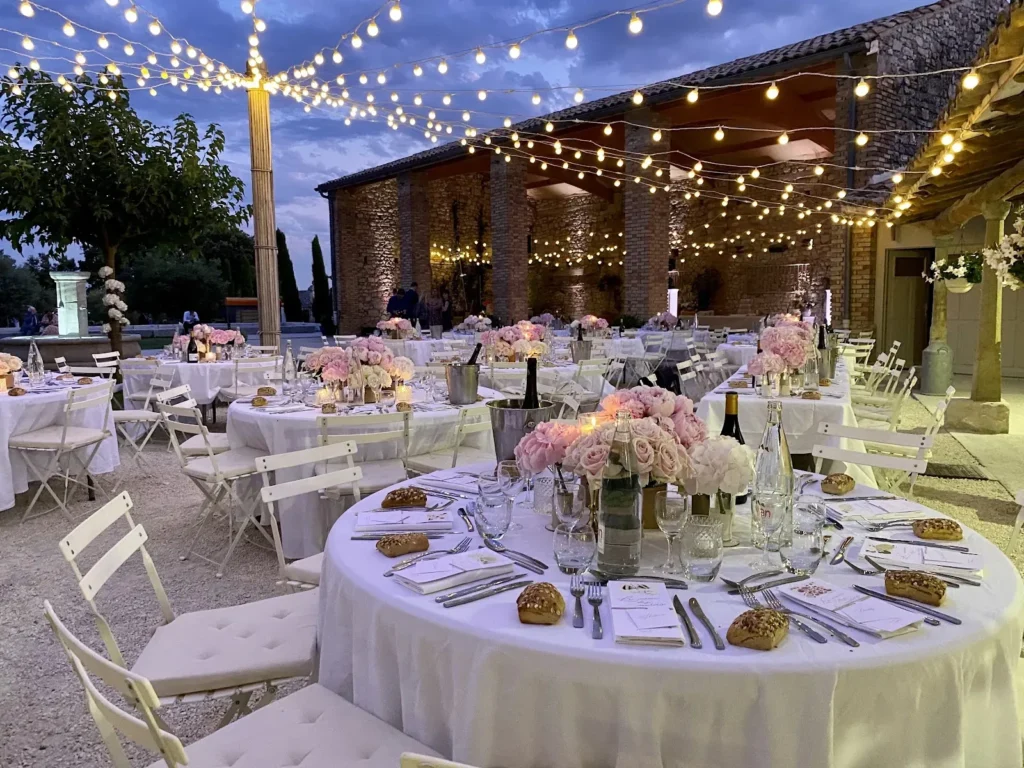 Tables rondes dressées de nappes blanches et centres floraux pour une réception en extérieur — Les Dînettes à Roulettes, traiteur de mariage dans le Gard