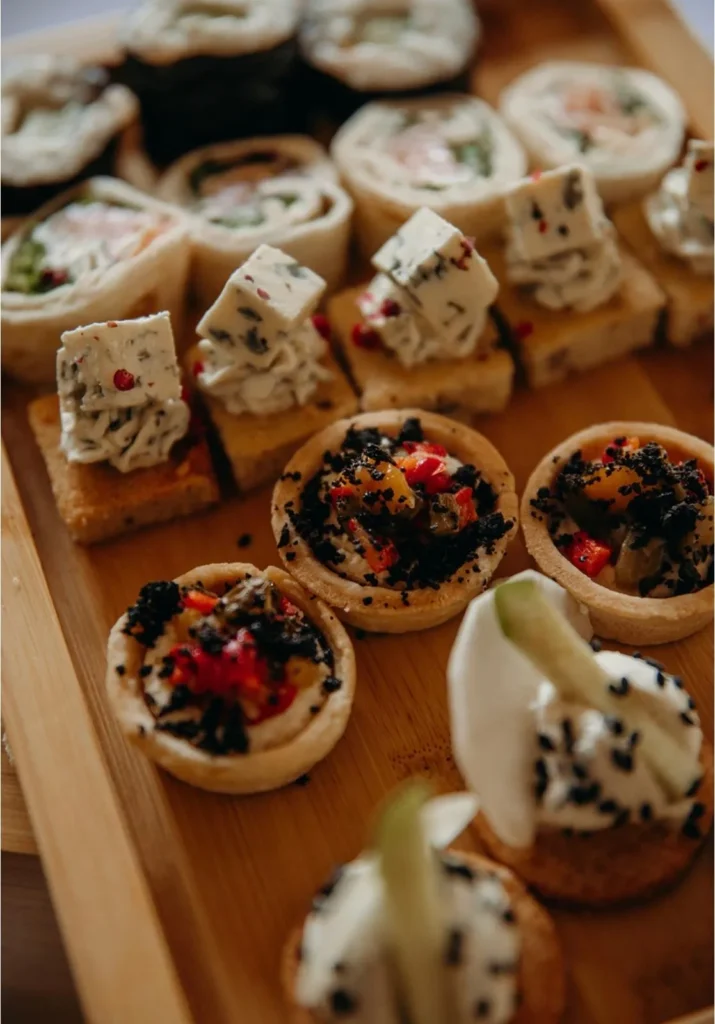Plateau en bois rempli de mignardises salées, roulés, toasts au fromage et tartelettes — Traiteur L’Évidence, Lattes
