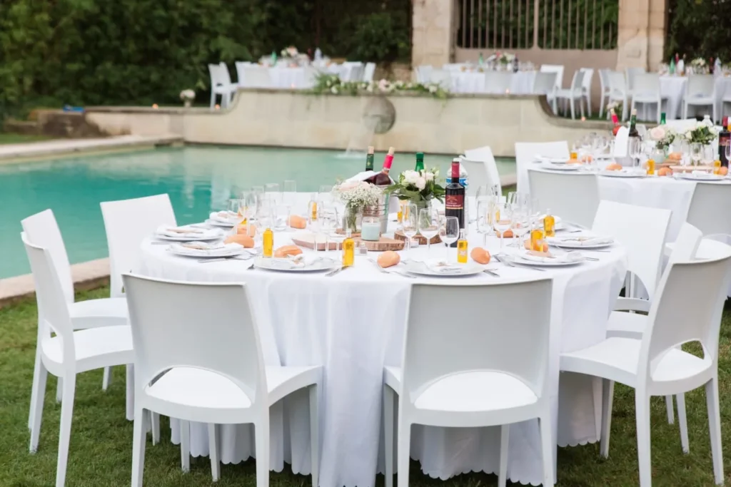 Tables rondes dressées pour un mariage en extérieur au bord d’une piscine verdoyante — Andrieux Traiteur, mariages à Lavérune