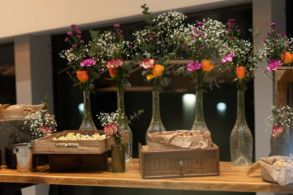 Table de réception en bois clair avec arrangements floraux et caisses d’amuse-bouches — La Petite Cuisine, Manduel