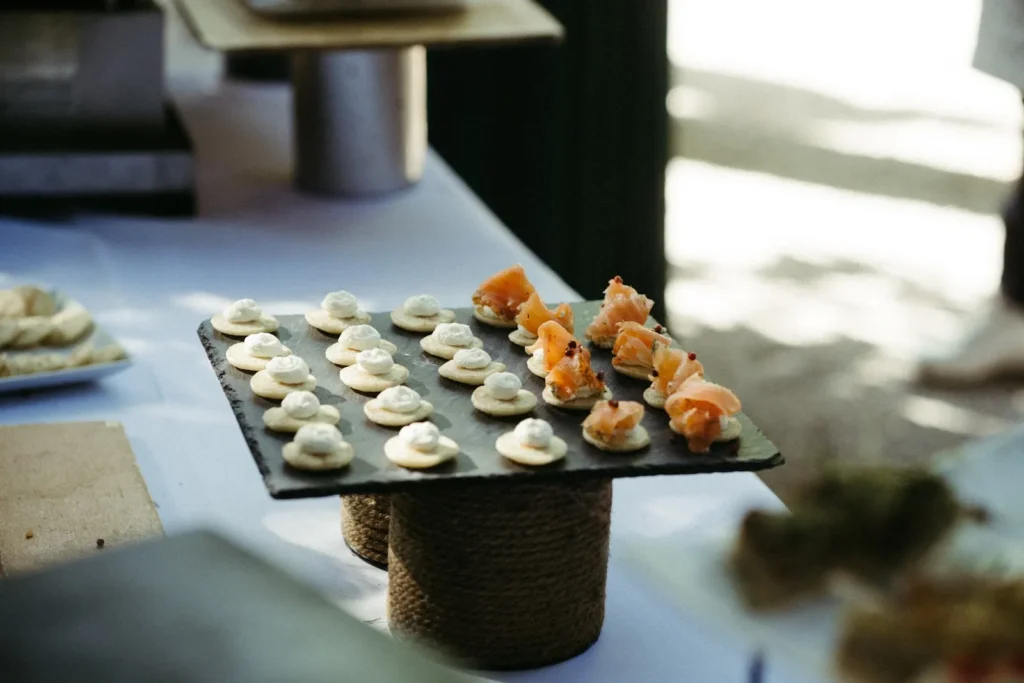 Plateau d’ardoise avec canapés au saumon fumé et crackers au fromage frais sur une table de réception — Traiteur d’Amélie, Mauguio
