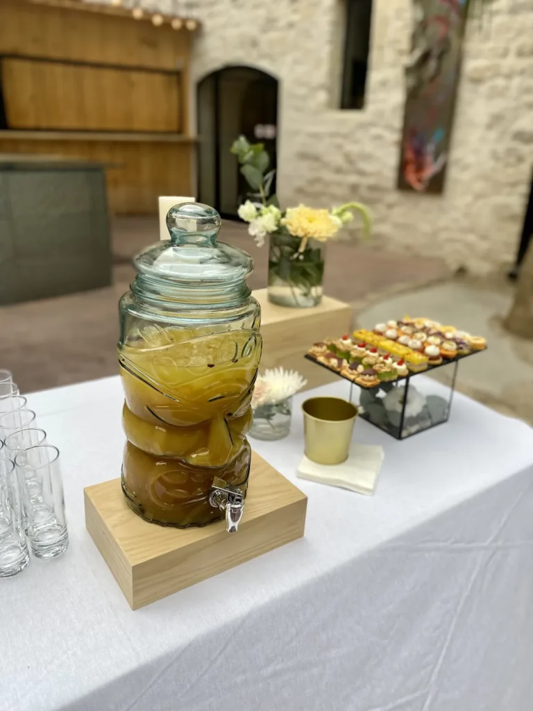 Distributeur de boisson fraîche et assortiment de mignardises salées sur table de réception — Traiteur d’Amélie, Mauguio