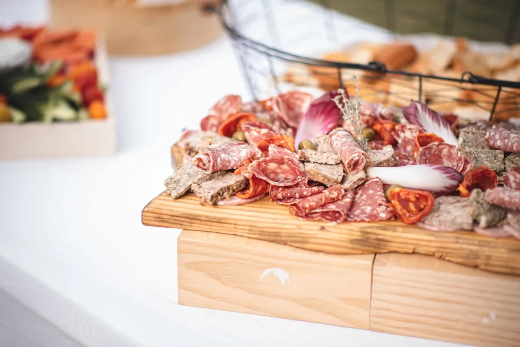 Plateau en bois rustique de charcuteries variées, pâtés, olives et endives — La Ferme des Saveurs, Méjannes-lès-Alès