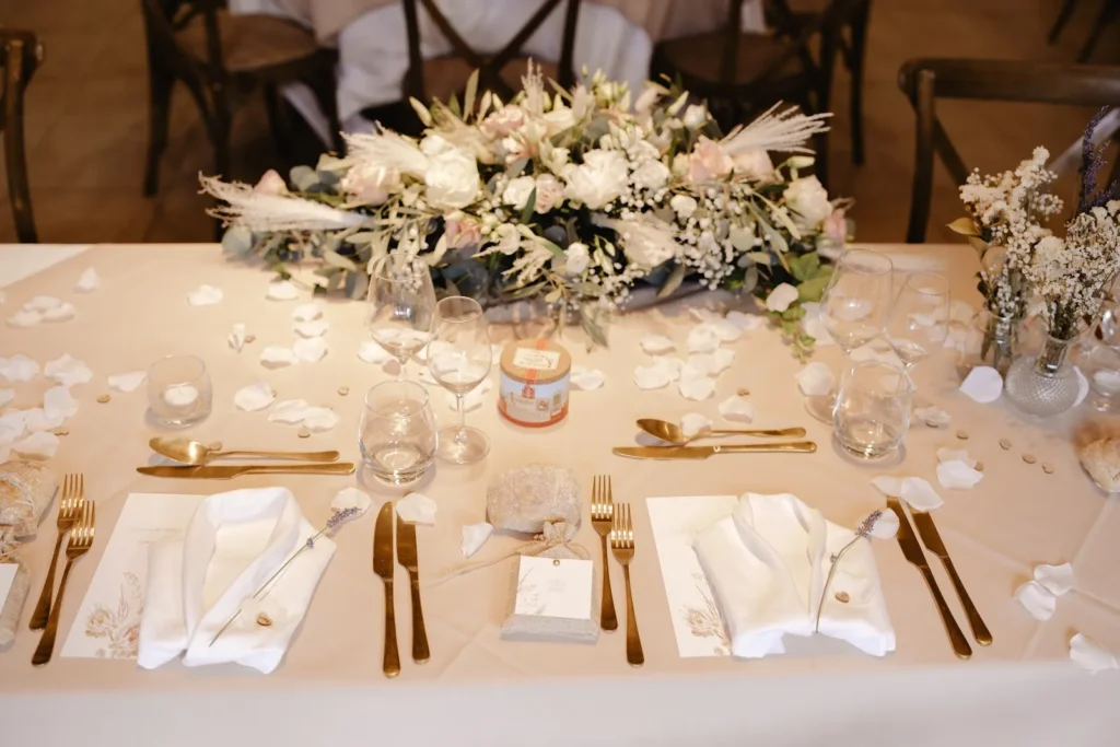Table de mariage dressée avec un centre de table floral et des couverts dorés — Cabiron Traiteur, mariages à Montpellier