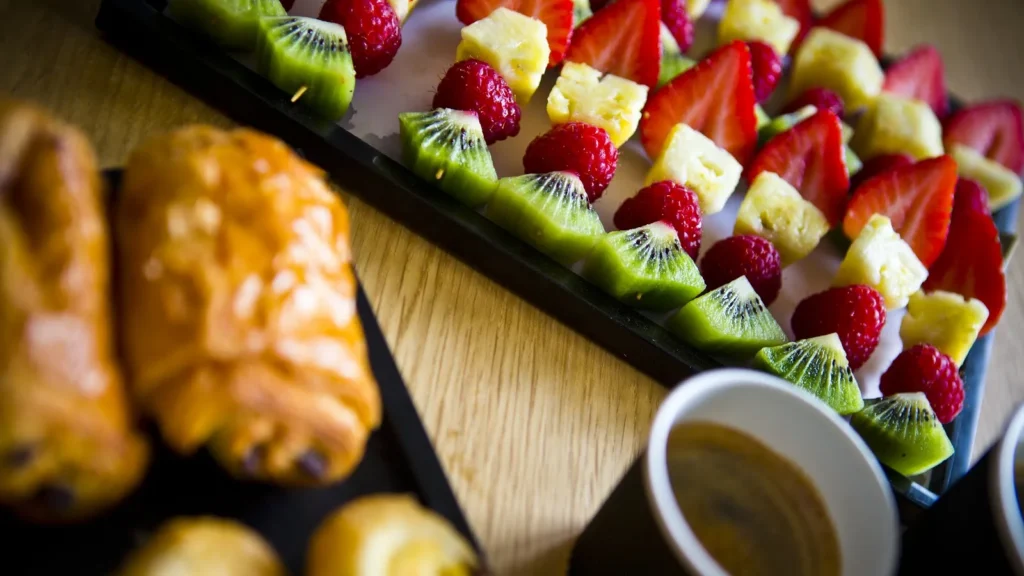Brochettes colorées de kiwi, framboise, ananas et fraise, accompagnées de viennoiseries et café — Husser Traiteur, Montpellier