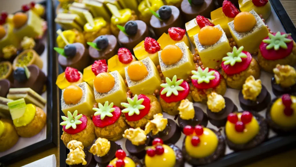 Assortiment coloré de mignardises et petits gâteaux individuels sur des plateaux pour un événement — Husser Traiteur, mariages à Montpellier