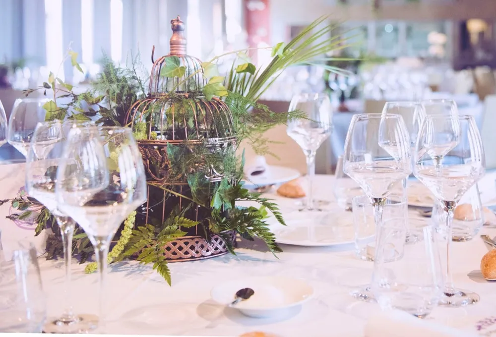 Table de réception dressée avec verres à vin et centre de table végétal en cage — Husser Traiteur, Montpellier
