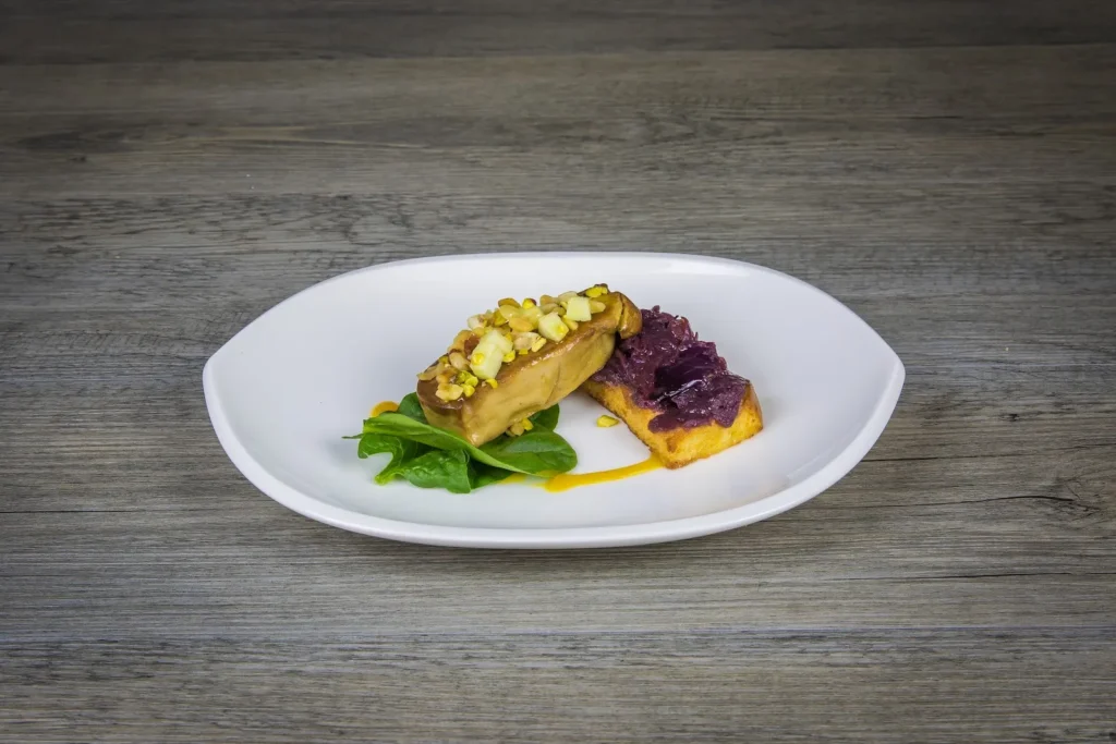 Plat de foie gras poêlé avec compotée de chou rouge et verdure sur assiette blanche — Traiteur Grand, Montpellier