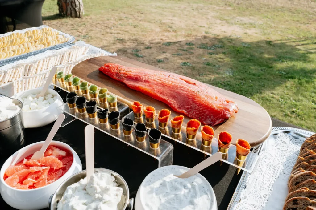 Une table de buffet en extérieur avec un filet de saumon frais sur une planche en bois — Traiteur Montgrand, mariages à Nîmes