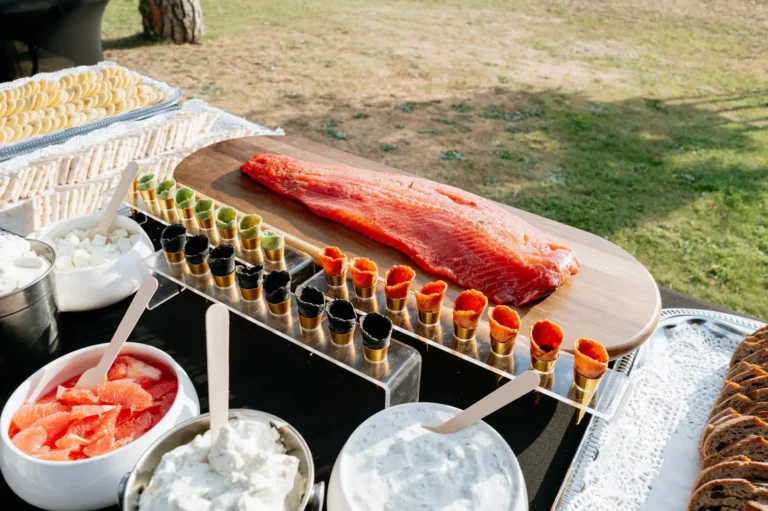 Une table de buffet en extérieur avec un filet de saumon frais sur une planche en bois — Traiteur Montgrand, mariages à Nîmes
