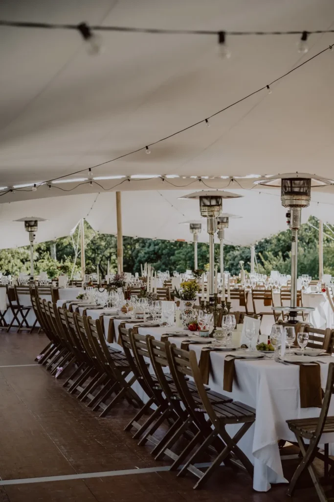 Longue table de mariage dressée sous une tente blanche avec centres de table floraux — Yello Event & Co, Nîmes