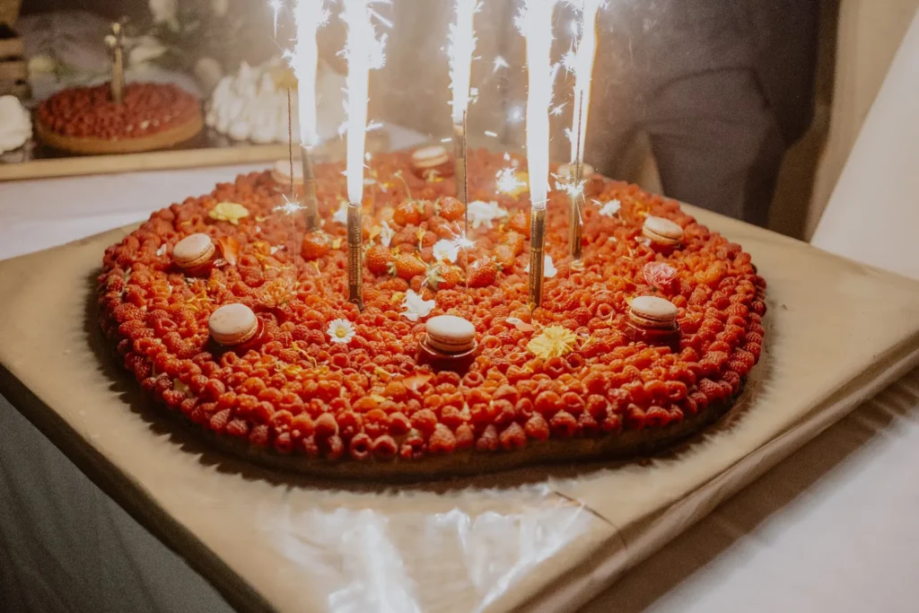 Grande tarte ronde garnie de framboises, fraises, macarons et fleurs avec cierges magiques — Yello Event & Co, Nîmes