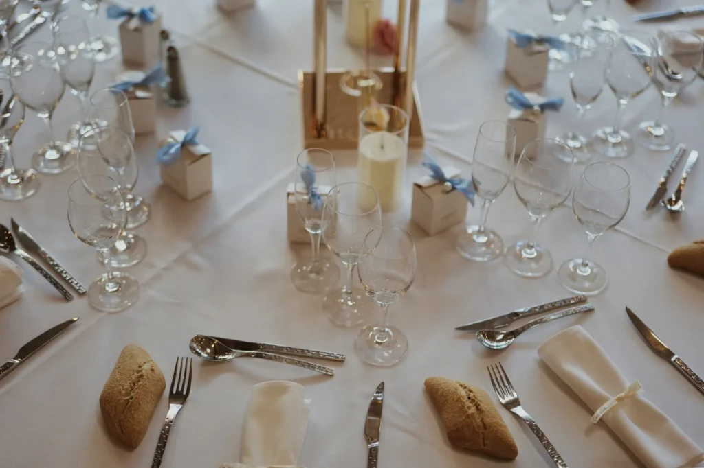 Table de mariage dressée avec nappe blanche, verres, couverts et petits pains — Traiteur Arqué, mariages à Ornaisons