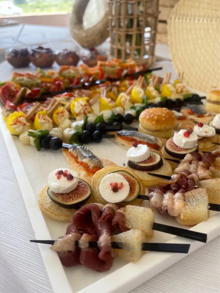 Plateau blanc rectangulaire de pièces cocktails variées avec brochettes, mini-burgers et canapés — Traiteur Niguès, Peyriac-de-Mer