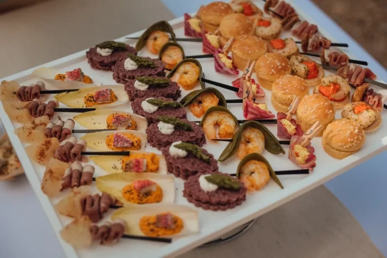 Grand plateau blanc de pièces cocktails salées avec brochettes de crevettes, mini-burgers et roulés — Traiteur Niguès, mariages à Peyriac-de-Mer