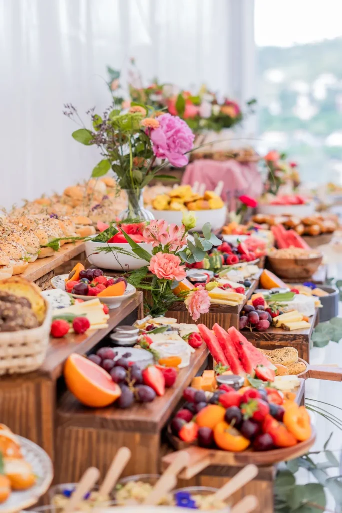 Buffet de mariage avec fromages, fruits frais, mini-sandwichs et décorations florales colorées — Grazing Montpellier, Saint-Georges-d’Orques