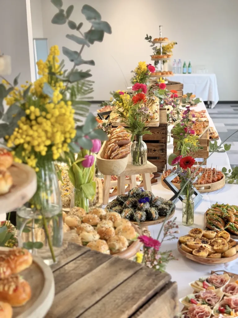 Grand buffet traiteur avec assortiment de mignardises salées et sucrées, décoré de fleurs colorées — Grazing Montpellier, Saint-Georges-d’Orques