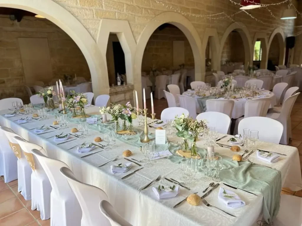 Table de réception de mariage dressée avec nappe blanche, chemin de table vert clair et centres floraux — La Toque Gourmande, traiteur de mariage à Uchaud